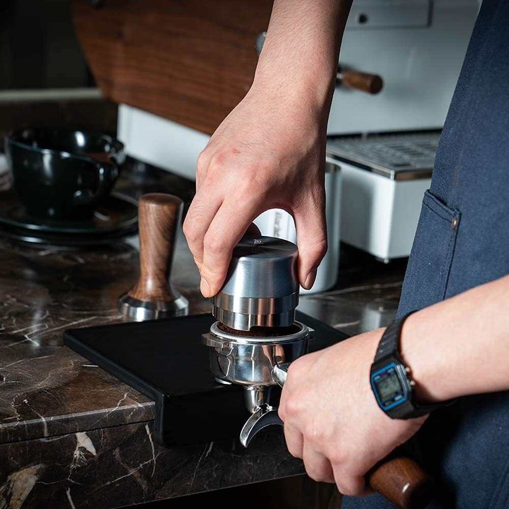 Close up of barista using coffee distributor on 58mm portafilter over L-shaped corner edge silicone mat.