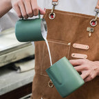 Barista steaming and frothing milk with green Culturbo pitcher.