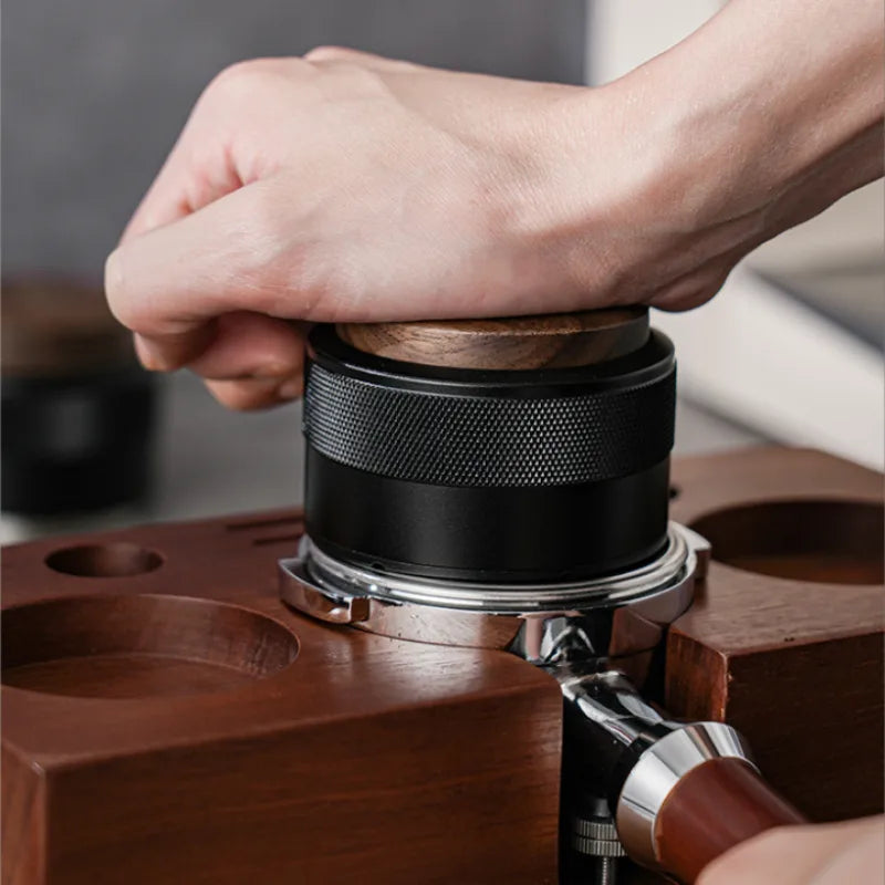 Barista pressing down the black anodized aluminum espresso tamper for constant mechanical pressure.