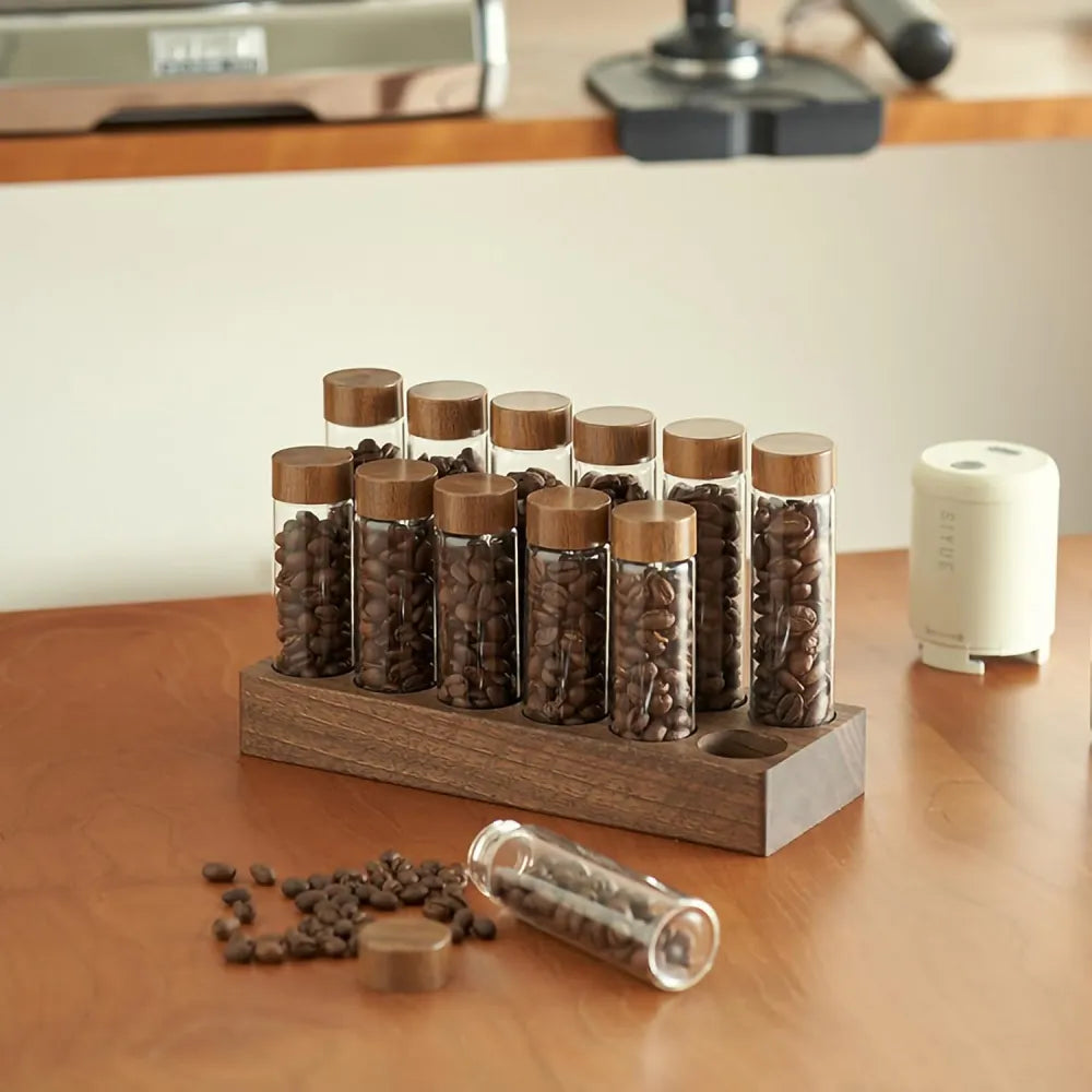 Elegant coffee bar organizer displaying espresso beans in glass vials on walnut base.