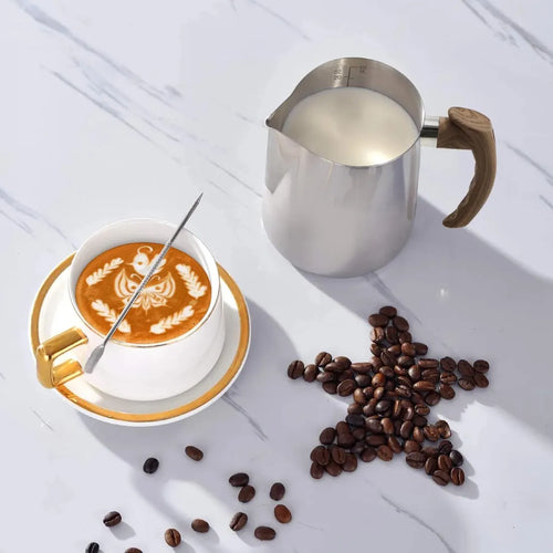 Barista creating beautiful latte art using 20oz milk frothing pitcher and pen.