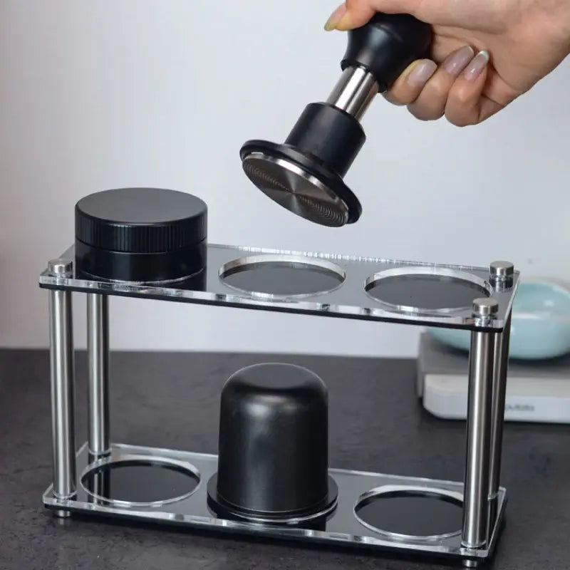 Home barista lifting an espresso tamper from an acrylic organizer stand