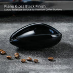 High-gloss piano black ceramic coffee bean single dose cup reflection on a minimalist coffee bar.