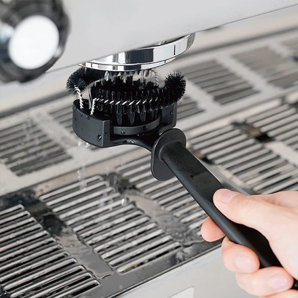 Barista using the counter-side group cleaner brush to scrub away stale coffee residues from the inner portafilter lock channel.
